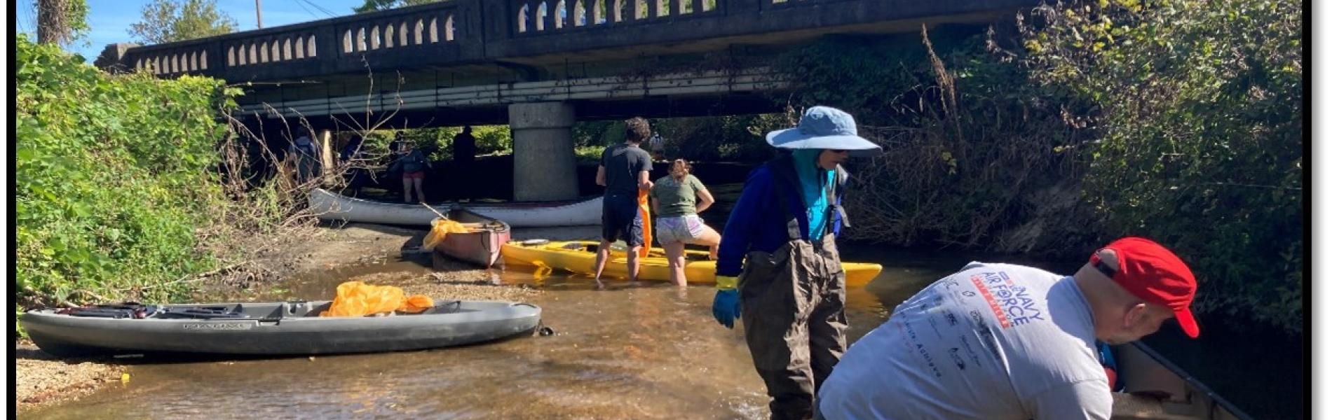 Volunteers wading in a stream picking up litter.