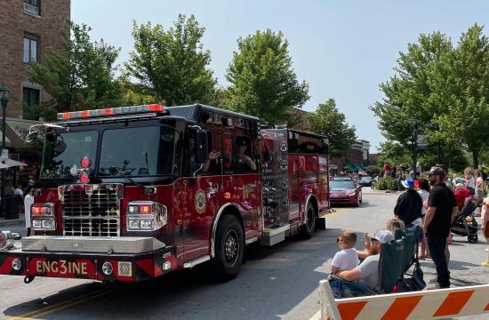 A red fire truck drives down Main Street during a parade.