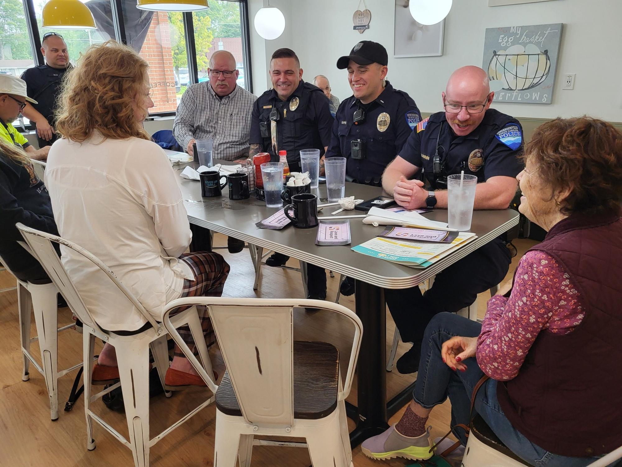 Officers sit with a group of community members at a Coffee with a Cop event